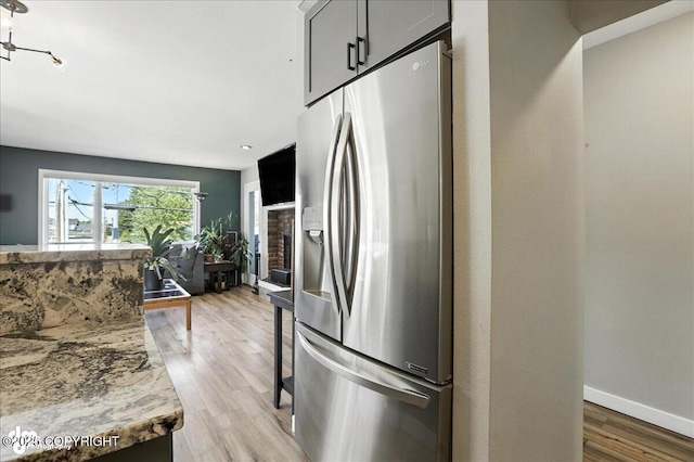3601 Oregon Dr # 1, Anchorage, AK 99517 - kitchen featuring stainless steel fridge, light wood finished floors, light stone counters, and open floor plan