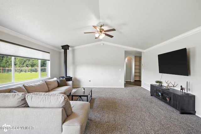 3098 N Lazy Aurora Cir, Palmer, AK 99645 - carpeted living area featuring a ceiling fan, a wood stove, crown molding, lofted ceiling, and arched walkways