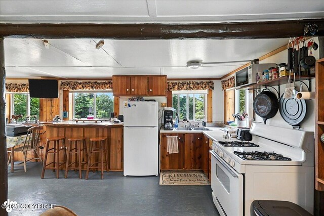 57541 Clam Diggers Ave, Clam Gulch, AK 99568 - kitchen with white appliances, brown cabinetry, and a kitchen bar