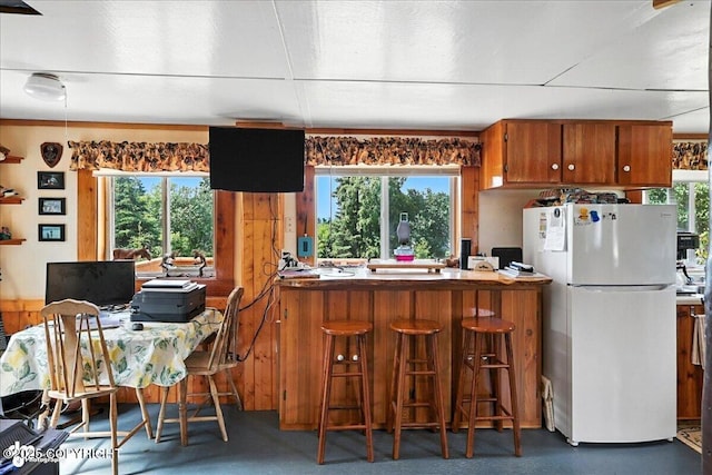 57541 Clam Diggers Ave, Clam Gulch, AK 99568 - kitchen featuring freestanding refrigerator, brown cabinetry, a peninsula, and a kitchen bar