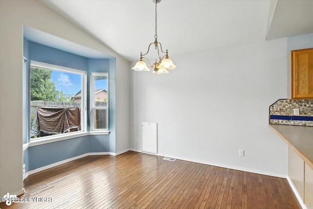 7851 Alpine View Cir, Anchorage, AK 99507 - unfurnished dining area featuring a chandelier, hardwood / wood-style floors, and lofted ceiling