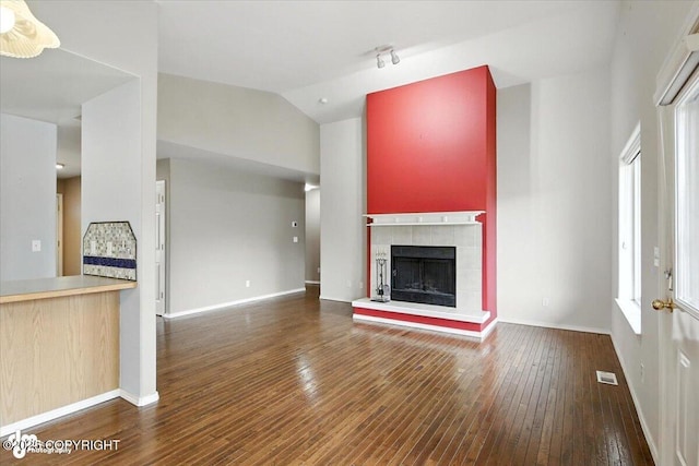 7851 Alpine View Cir, Anchorage, AK 99507 - unfurnished living room featuring wood-type flooring, a tile fireplace, lofted ceiling, and rail lighting
