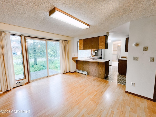 505 Unimak St, Petersburg, AK 99833 - kitchen with freestanding refrigerator, a baseboard radiator, a peninsula, light wood-style floors, and a textured ceiling
