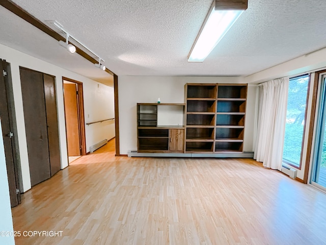 505 Unimak St, Petersburg, AK 99833 - unfurnished living room featuring a baseboard heating unit, a textured ceiling, and light wood finished floors