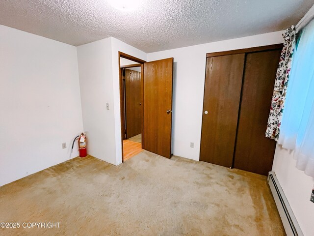 505 Unimak St, Petersburg, AK 99833 - unfurnished bedroom featuring baseboard heating, carpet floors, a textured ceiling, and a closet