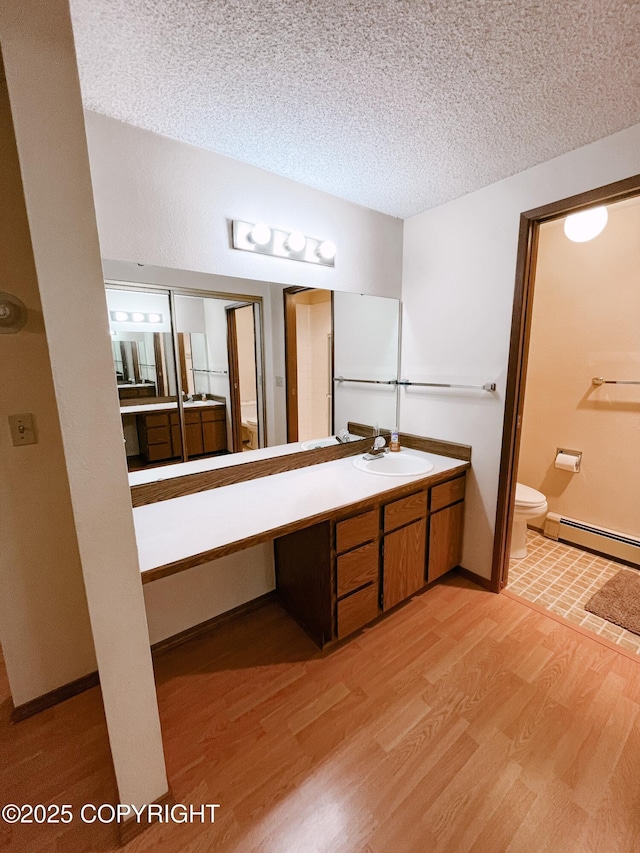 505 Unimak St, Petersburg, AK 99833 - bathroom featuring a baseboard radiator, wood finished floors, vanity, and a textured ceiling