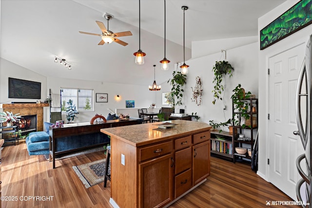 9166 Eagle River Ln, Eagle River, AK 99577 - kitchen featuring a lit fireplace, dark wood-style floors, ceiling fan, a center island, and hanging light fixtures