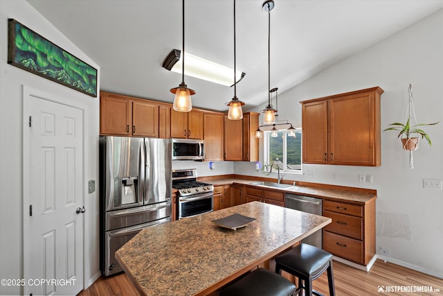 9166 Eagle River Ln, Eagle River, AK 99577 - kitchen featuring appliances with stainless steel finishes, vaulted ceiling, a breakfast bar area, brown cabinets, and a center island