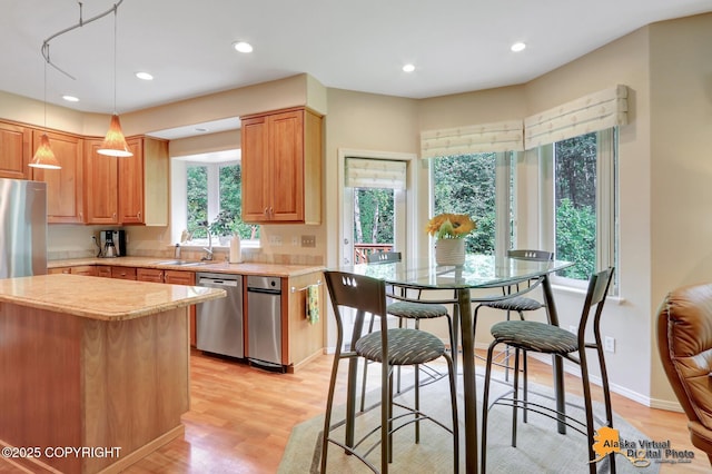 3931 Moonstar Cir, Anchorage, AK 99516 - kitchen featuring stainless steel dishwasher, light wood finished floors, recessed lighting, hanging light fixtures, and light stone countertops