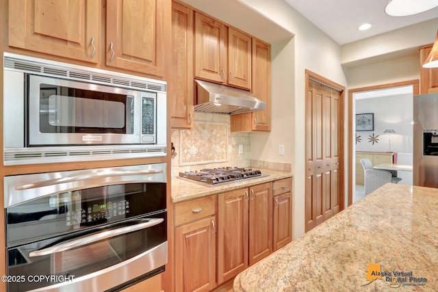3931 Moonstar Cir, Anchorage, AK 99516 - kitchen featuring appliances with stainless steel finishes, under cabinet range hood, backsplash, light stone countertops, and recessed lighting
