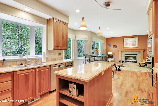 3931 Moonstar Cir, Anchorage, AK 99516 - kitchen featuring stainless steel appliances, light stone countertops, a tile fireplace, light wood-type flooring, and a center island