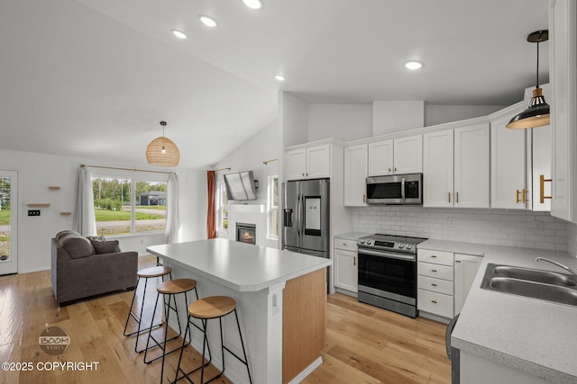 1460 E Esty Dr, Palmer, AK 99645 - kitchen with appliances with stainless steel finishes, vaulted ceiling, a breakfast bar, decorative backsplash, and white cabinets