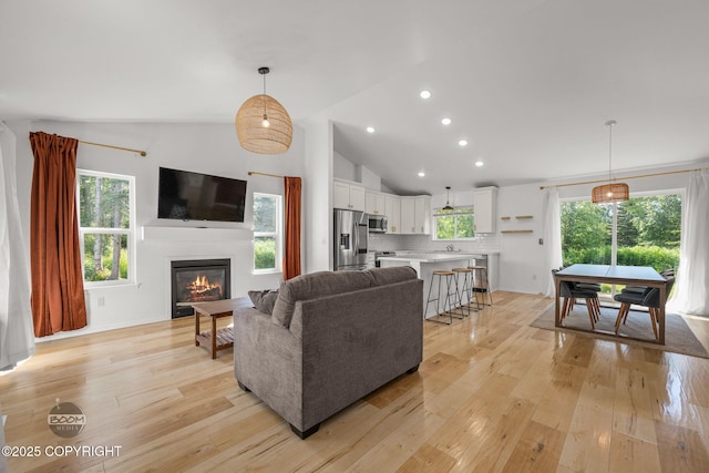 1460 E Esty Dr, Palmer, AK 99645 - living area featuring light wood finished floors, a glass covered fireplace, recessed lighting, healthy amount of natural light, and high vaulted ceiling