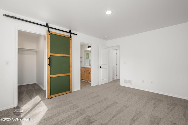 1460 E Esty Dr, Palmer, AK 99645 - unfurnished bedroom with carpet flooring, a spacious closet, a barn door, and ensuite bathroom