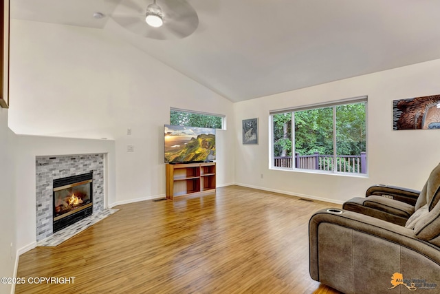 7862 Spruce St Unit 7B, Anchorage, AK 99507 - living room with a ceiling fan, light wood-style floors, a tile fireplace, and high vaulted ceiling