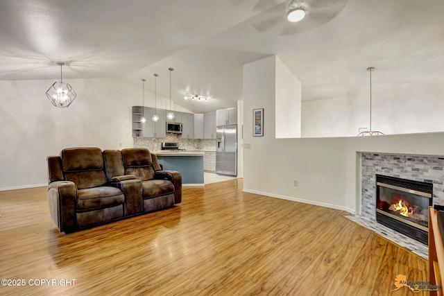 7862 Spruce St Unit 7B, Anchorage, AK 99507 - living area with ceiling fan, light wood-style floors, vaulted ceiling, and a fireplace with flush hearth