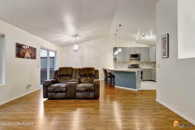 7862 Spruce St Unit 7B, Anchorage, AK 99507 - living room with lofted ceiling, light wood-style flooring, a chandelier, and track lighting
