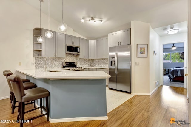7862 Spruce St Unit 7B, Anchorage, AK 99507 - kitchen with appliances with stainless steel finishes, a peninsula, a breakfast bar area, open shelves, and light wood finished floors