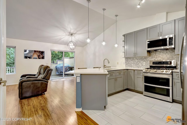 7862 Spruce St Unit 7B, Anchorage, AK 99507 - kitchen featuring stainless steel appliances, gray cabinets, a peninsula, open floor plan, and vaulted ceiling