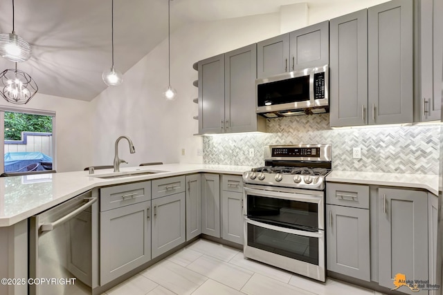 7862 Spruce St Unit 7B, Anchorage, AK 99507 - kitchen with appliances with stainless steel finishes, gray cabinetry, a peninsula, vaulted ceiling, and decorative backsplash