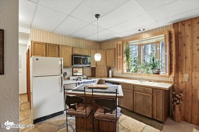 311 Alpine Meadows Ave, Girdwood, AK 99587 - kitchen with white appliances, brown cabinets, wood walls, tile counters, and pendant lighting