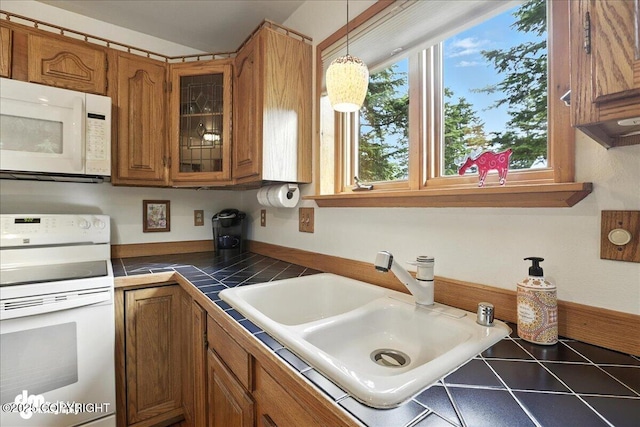 311 Alpine Meadows Ave, Girdwood, AK 99587 - kitchen with white appliances, brown cabinetry, tile counters, glass insert cabinets, and hanging light fixtures