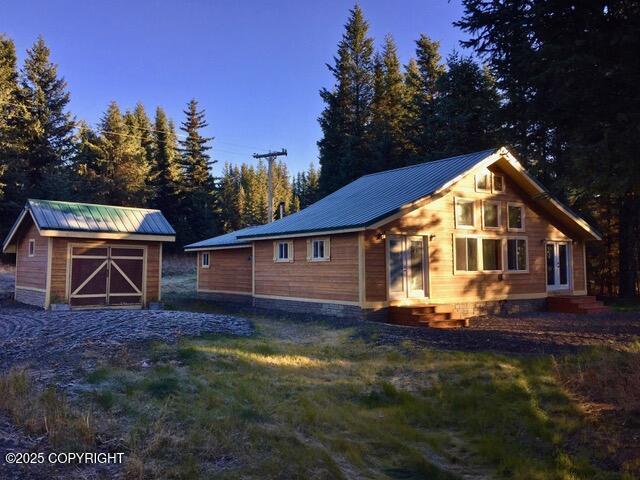 40996 Woodman Ln, Homer, AK 99603 - view of property exterior featuring a metal roof, entry steps, a shed, and a yard