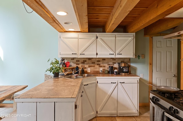 40996 Woodman Ln, Homer, AK 99603 - kitchen with stainless steel gas range oven, decorative backsplash, light tile patterned floors, beamed ceiling, and white cabinetry