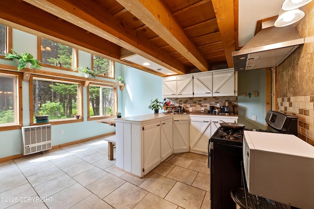 40996 Woodman Ln, Homer, AK 99603 - kitchen with gas stove, light tile patterned floors, a peninsula, exhaust hood, and a wooden ceiling with exposed beams
