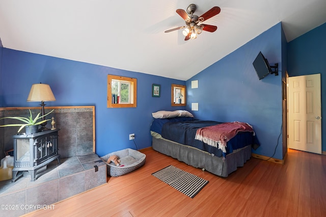 40996 Woodman Ln, Homer, AK 99603 - bedroom featuring a wood stove, wood finished floors, vaulted ceiling, and a ceiling fan