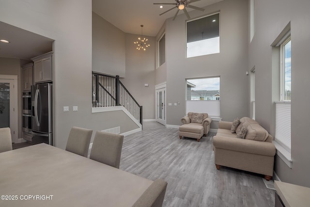5062 E Calf Cir, Wasilla, AK 99654 - living room featuring stairway, a towering ceiling, light wood finished floors, a ceiling fan, and a chandelier