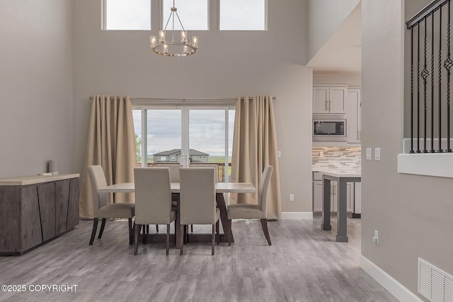 5062 E Calf Cir, Wasilla, AK 99654 - dining area with a towering ceiling, a chandelier, plenty of natural light, and light wood-type flooring