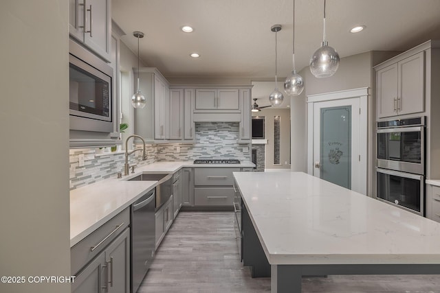 5062 E Calf Cir, Wasilla, AK 99654 - kitchen featuring appliances with stainless steel finishes, gray cabinetry, a center island, tasteful backsplash, and light wood-style floors