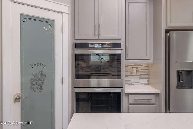 5062 E Calf Cir, Wasilla, AK 99654 - kitchen featuring stainless steel appliances, gray cabinetry, decorative backsplash, and light stone countertops