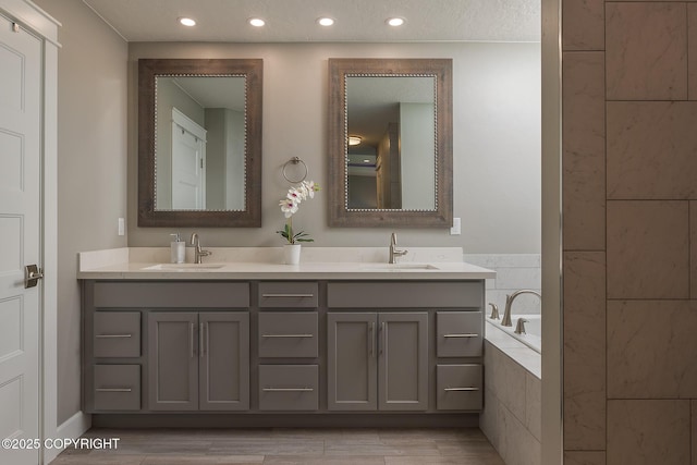 5062 E Calf Cir, Wasilla, AK 99654 - bathroom with double vanity, a relaxing tiled tub, recessed lighting, and wood finished floors