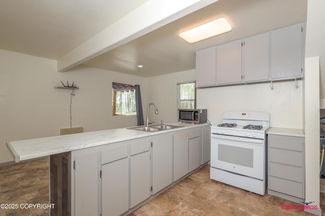 20057 E Caswell Lakes Rd, Willow, AK 99688 - kitchen featuring gas range gas stove, stainless steel microwave, a peninsula, light countertops, and stone finish flooring