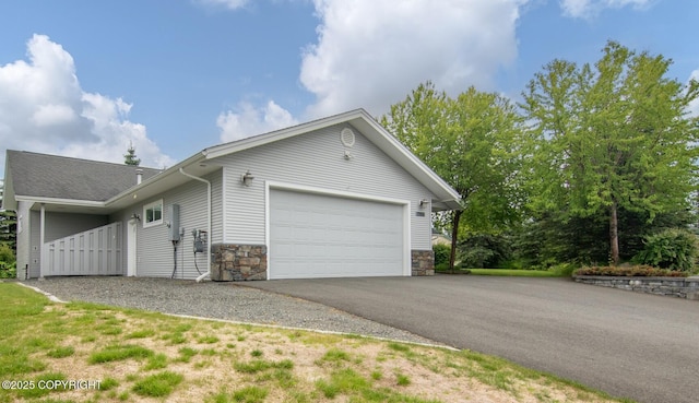 1103 Inlet Woods Dr, Kenai, AK 99611 - view of property exterior featuring an attached garage, stone siding, and driveway