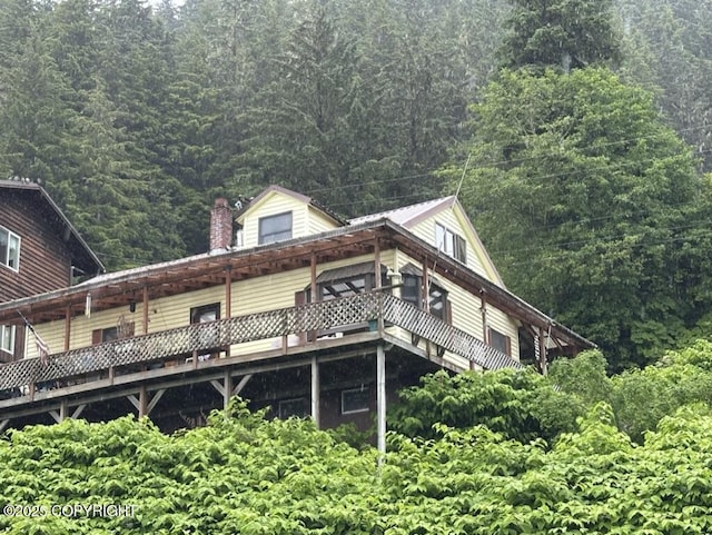 339 Cassiar St, Wrangell, AK 99929 - view of side of property featuring a wooded view, a chimney, and a deck