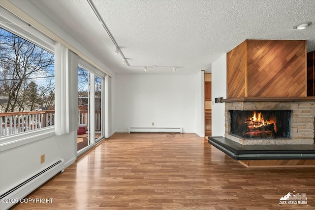 1521 Cache Dr, Anchorage, AK 99507 - unfurnished living room featuring baseboard heating, a stone fireplace, a textured ceiling, and wood finished floors