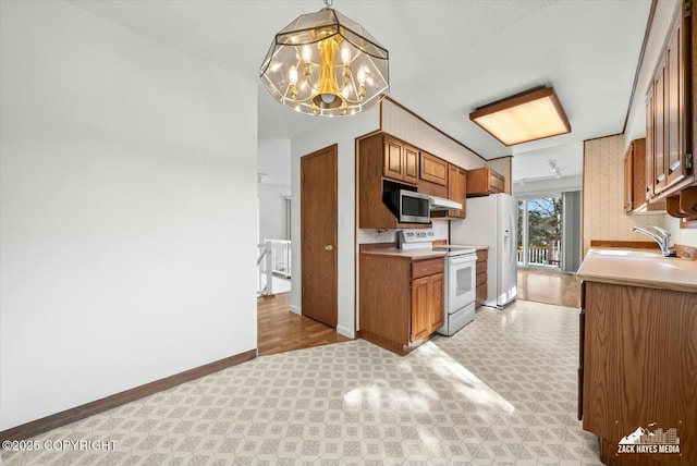 1521 Cache Dr, Anchorage, AK 99507 - kitchen featuring white appliances, brown cabinets, light flooring, a chandelier, and light countertops