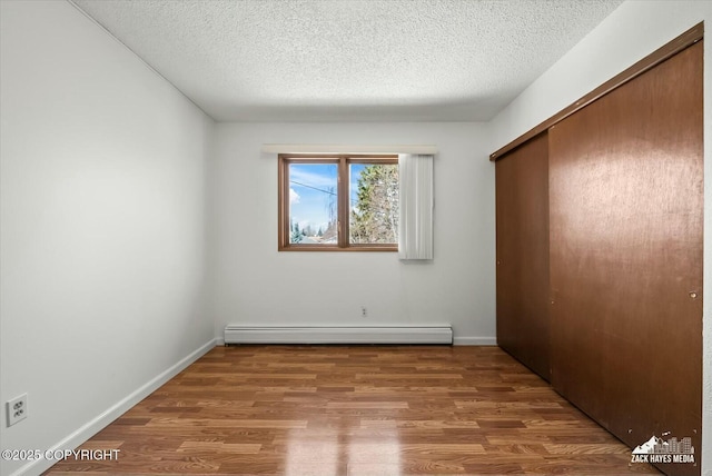 1521 Cache Dr, Anchorage, AK 99507 - unfurnished bedroom featuring a baseboard radiator, a closet, wood finished floors, and a textured ceiling
