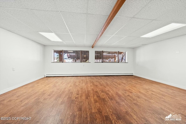 1521 Cache Dr, Anchorage, AK 99507 - unfurnished room featuring a drop ceiling, wood finished floors, healthy amount of natural light, and a baseboard heating unit