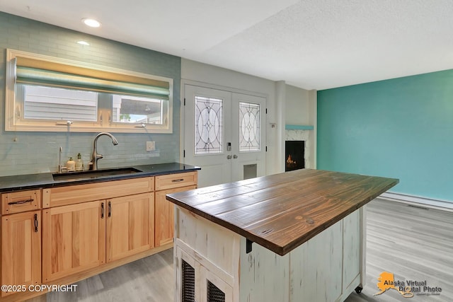 3265 Montclair Ct # 17E, Anchorage, AK 99503 - kitchen featuring a warm lit fireplace, butcher block countertops, light wood-style floors, a kitchen island, and backsplash