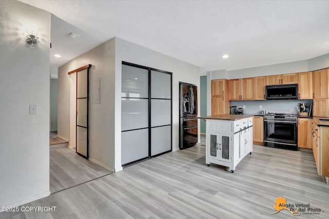 3265 Montclair Ct # 17E, Anchorage, AK 99503 - kitchen with stainless steel range oven, black microwave, fridge with ice dispenser, light wood-type flooring, and dark countertops