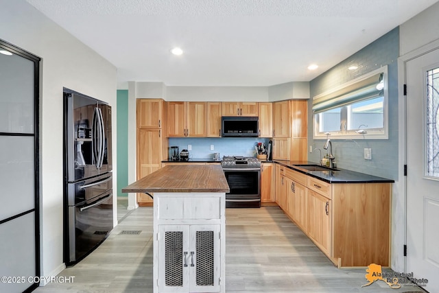 3265 Montclair Ct # 17E, Anchorage, AK 99503 - kitchen featuring refrigerator with ice dispenser, stainless steel gas range oven, black microwave, light wood-type flooring, and recessed lighting
