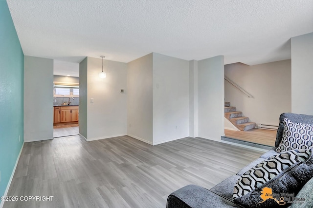 3265 Montclair Ct # 17E, Anchorage, AK 99503 - living area with wood finished floors, stairs, a textured ceiling, and a baseboard radiator