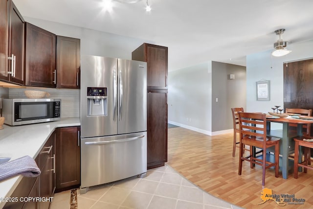 3306 E 19th Ct, Anchorage, AK 99508 - kitchen featuring stainless steel appliances, light countertops, dark brown cabinets, light wood-type flooring, and a ceiling fan