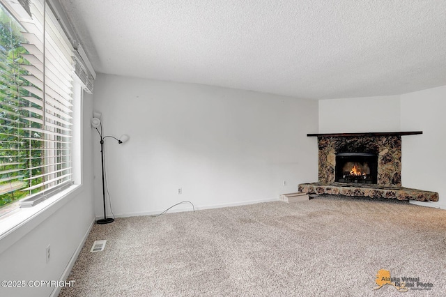 791 N Yakima St, Wasilla, AK 99654 - unfurnished living room featuring a stone fireplace, a textured ceiling, and carpet flooring