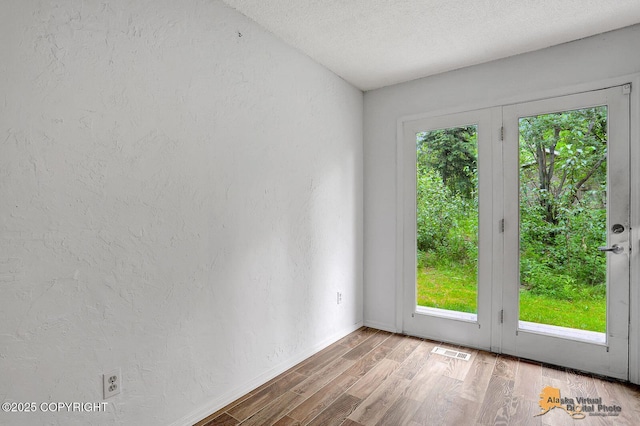 791 N Yakima St, Wasilla, AK 99654 - spare room featuring plenty of natural light, wood finished floors, a textured ceiling, a textured wall, and french doors