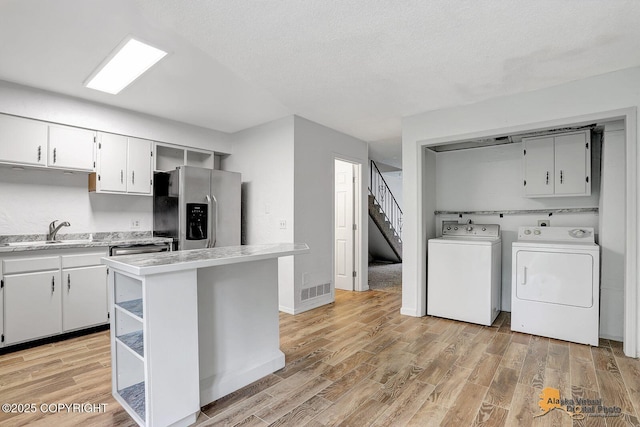 791 N Yakima St, Wasilla, AK 99654 - kitchen with appliances with stainless steel finishes, light wood-style flooring, light countertops, washing machine and clothes dryer, and a textured ceiling